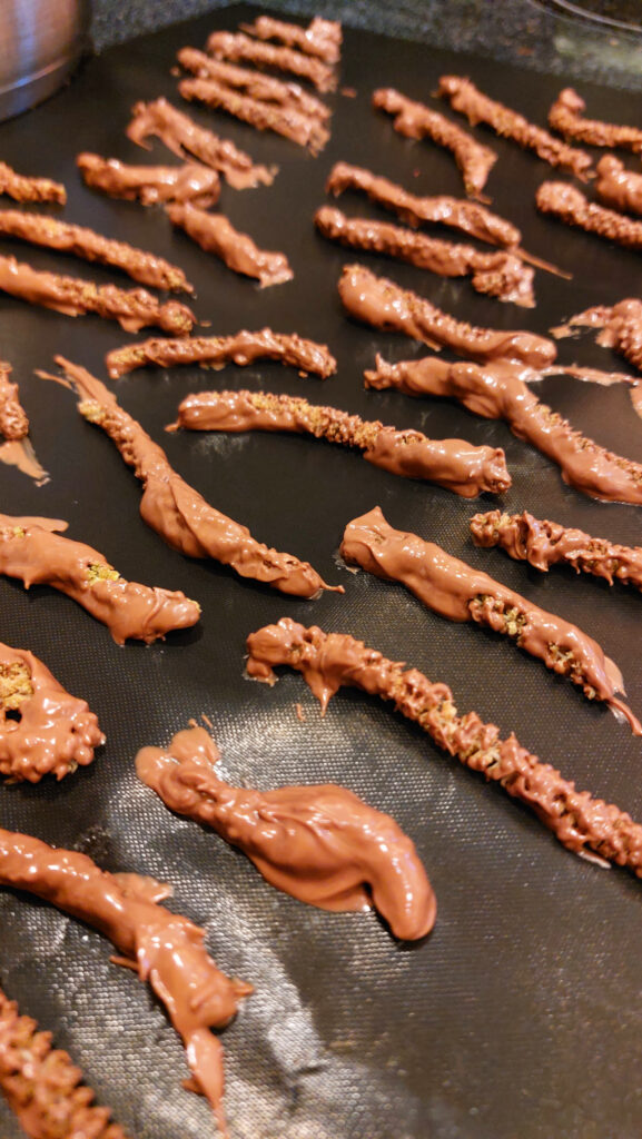 Haselkätzchen mit Schokoladenüberzug kühlen auf einem Backpapier ab.