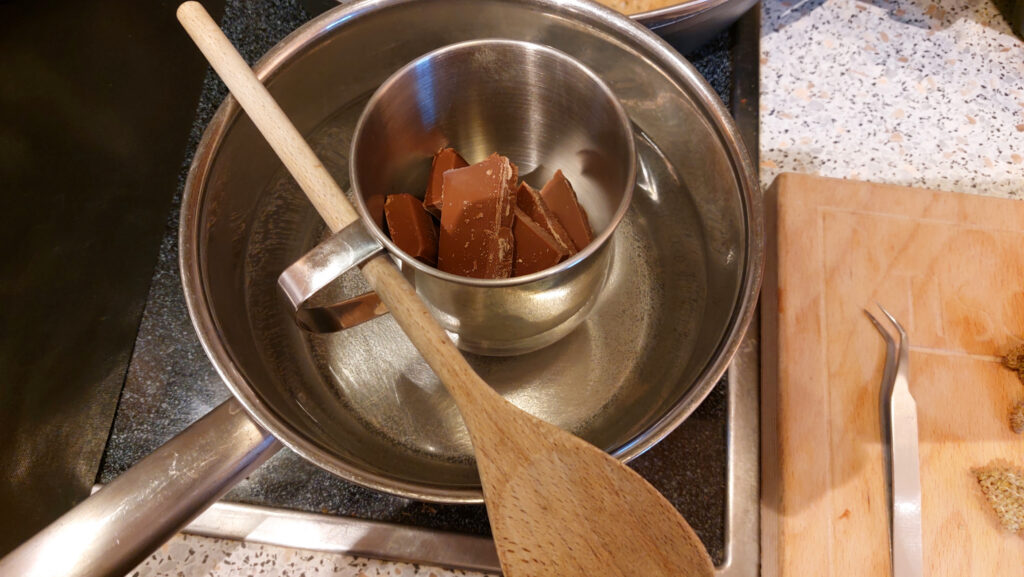 Edelstahlbecher im Wasserbad. Praxistipp: Der Becher kann mit einem Kochlöffel im Wasserbad fixiert werden.
