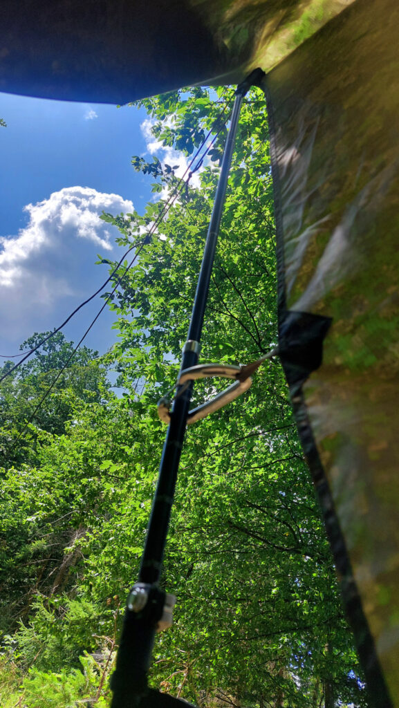 Blick aus dem freistehenden Tarp-Aufbau mit Trekkingstock nach draußen in den Himmel