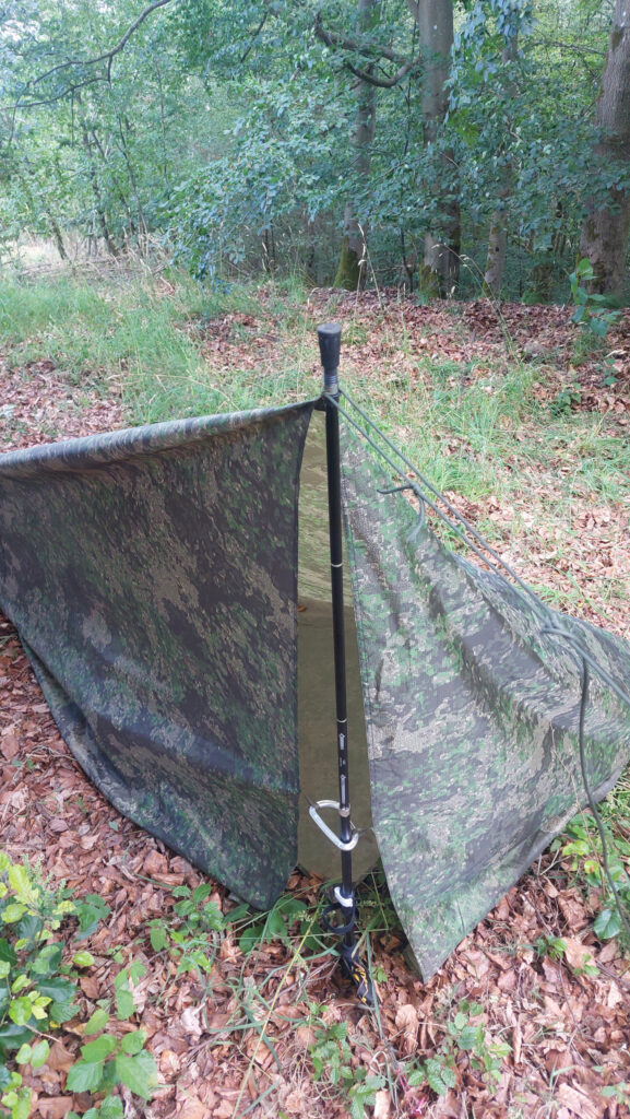 freistehender Tarp-Aufbau eines Helikon-Tex-Supertarps in Pencott Wildwood mit Trekkingstock